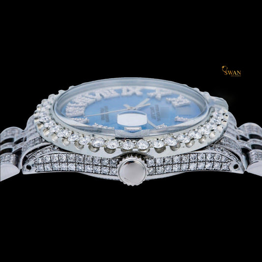 White iced-out watch with a blue mother-of-pearl dial, diamond-studded roman numerals, and a link band by swandiamond