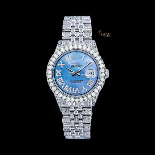 White iced-out watch with a blue mother-of-pearl dial, diamond-studded roman numerals, and a link band by swandiamond